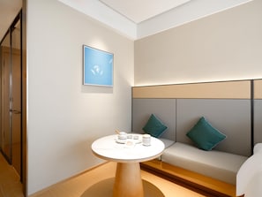 A modern hotel room with a round table, a sofa with teal cushions, and a framed artwork on the wall. - Ji Guangzhou Baiyun Intern Conference Center Qifu (Guangzhou)