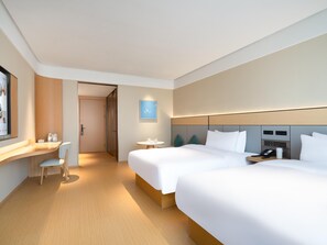 Una habitación de hotel moderna con dos camas, un escritorio y una mesita.
