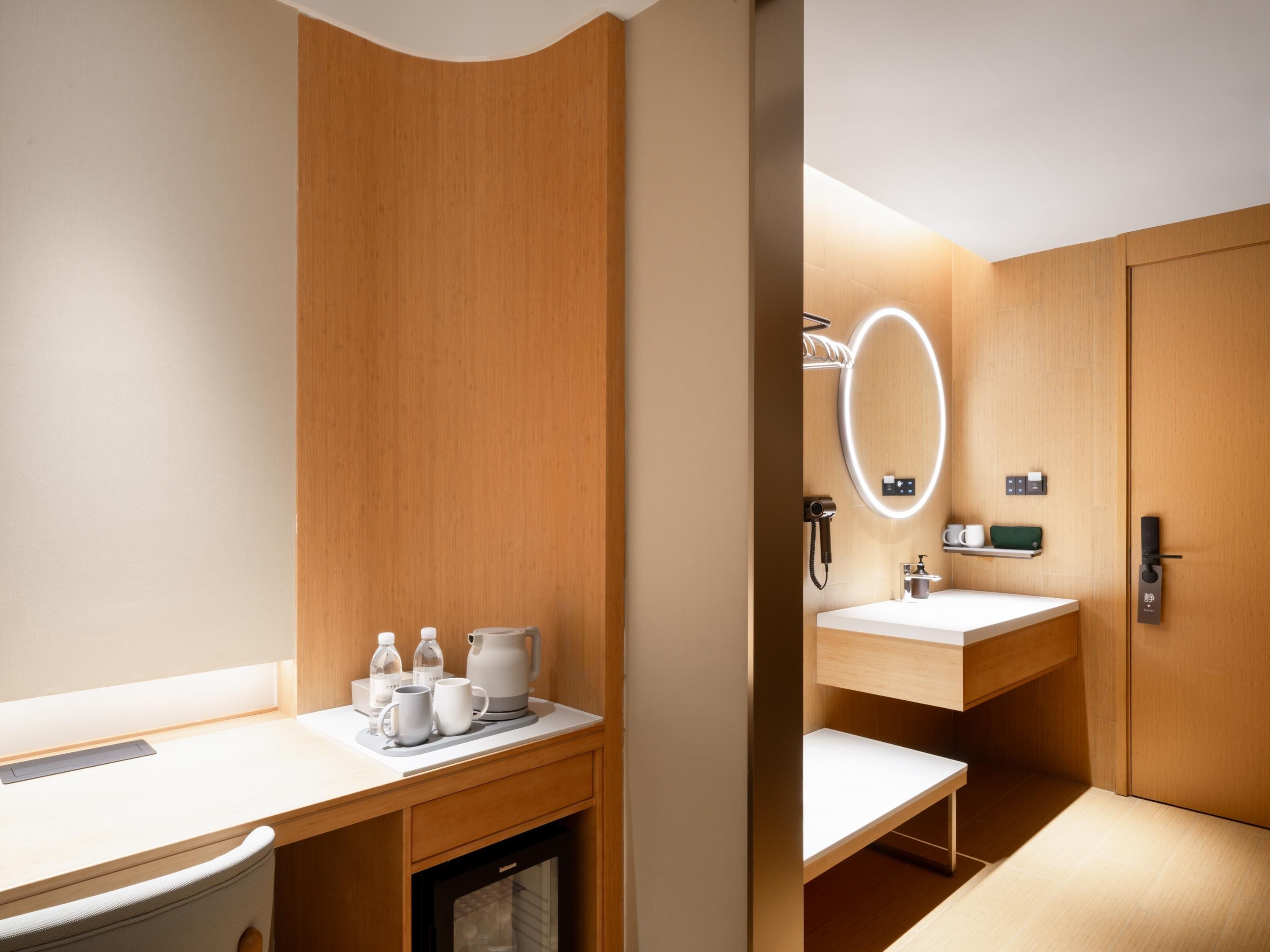 A modern bathroom with a wooden vanity, a sink, a mirror with built-in lighting, and a towel rack.