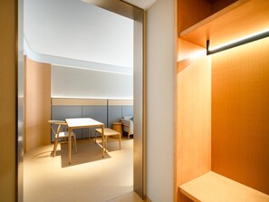 Una habitación moderna con un diseño minimalista, que incluye un escritorio de madera, dos sillas y una mesita pequeña.