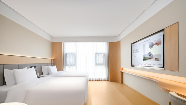 Een hotelkamer met een groot bed, een bureau en een televisie aan de muur.