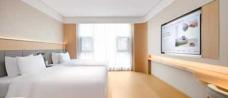 Ein Hotelzimmer mit einem großen Bett, einem Schreibtisch und einem an der Wand befestigten Fernseher.
