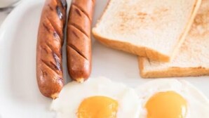 Une assiette avec deux saucisses grillées, deux œufs au plat et deux tranches de pain grillé.