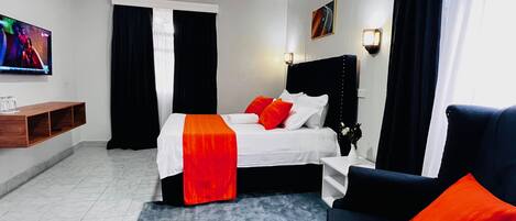 Una habitación de hotel con cama, televisor, escritorio y sofá.