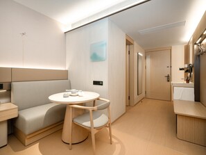 A modern, compact room with a round table, a cushioned bench, and a single chair. - Ji Hotel Guangzhou Baiyun Airport Renhe Metro (Guangzhou)