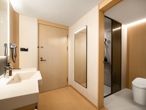 Ein modernes Badezimmer mit einem Holzkosmetikschrank, einem großen Spiegel, einer Dusche mit Handbrause und einer Toilette.