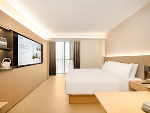 A modern hotel room with a large bed, a bedside table, a flat-screen TV mounted on the wall, and a view of the city through large windows. - Ji Hotel Guangzhou Baiyun Airport Renhe Metro (Guangzhou)