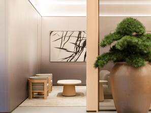 A modern room with a large potted plant, a round table, and two chairs.