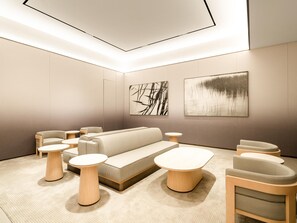 Un salon moderne et bien éclairé, avec un canapé, des fauteuils et des tables rondes.
