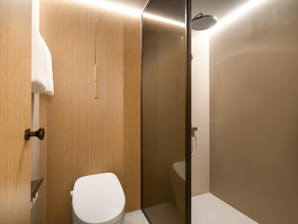 Un baño moderno con un tocador de madera, un inodoro blanco y una zona de ducha con paredes de vidrio.