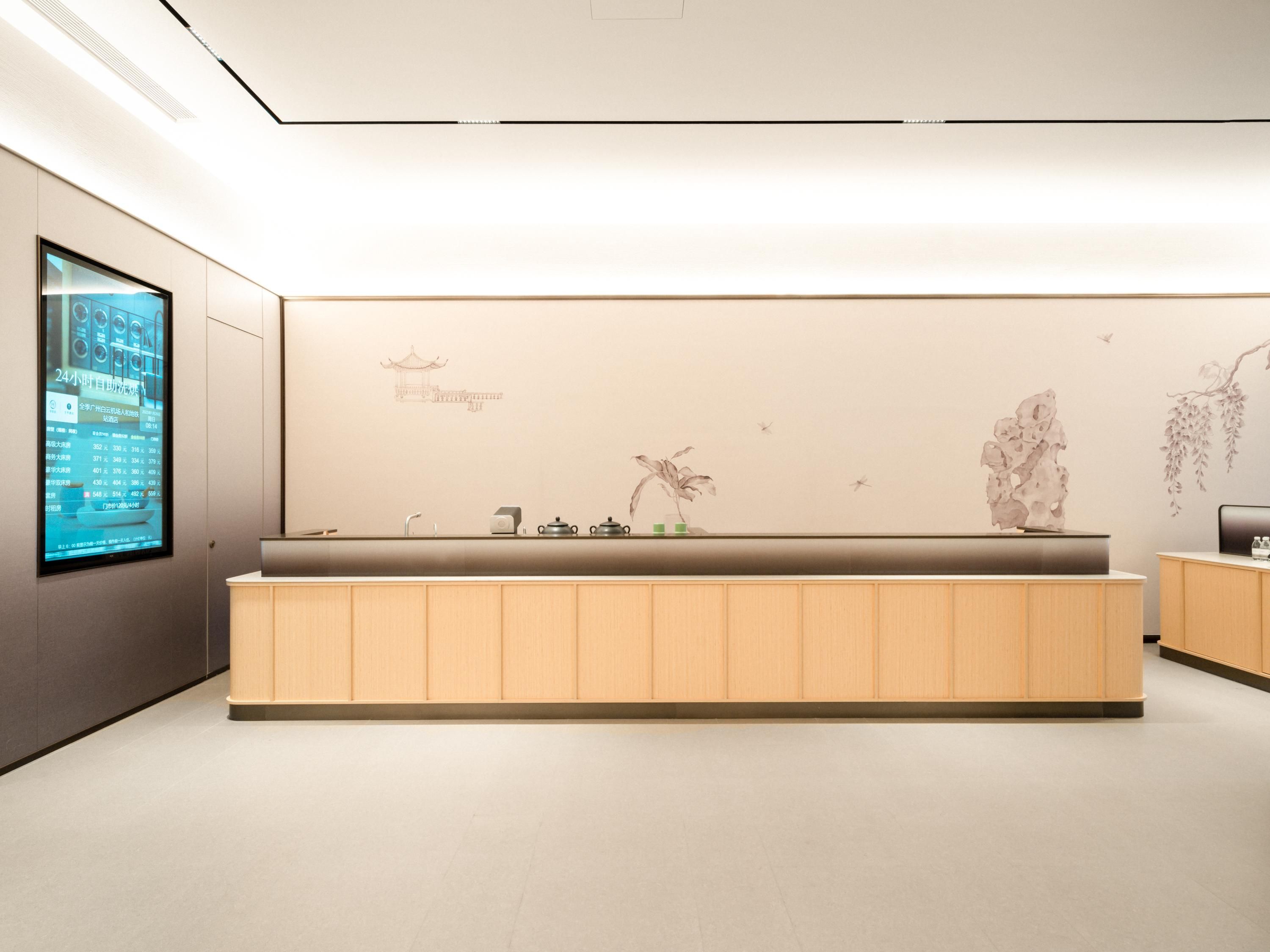 Uma área de recepção moderna com tela digital, balcão de atendimento e detalhes decorativos na parede.
