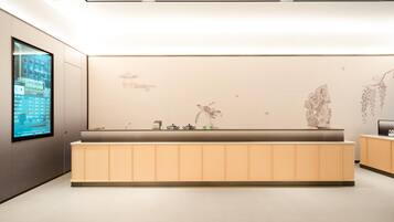 Uma área de recepção moderna com tela digital, balcão de atendimento e detalhes decorativos na parede.