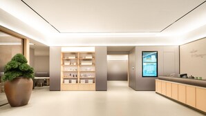 A modern reception area with a wooden reception desk, a large potted plant, and a wall-mounted digital display. - Ji Hotel Guangzhou Baiyun Airport Renhe Metro (Guangzhou)
