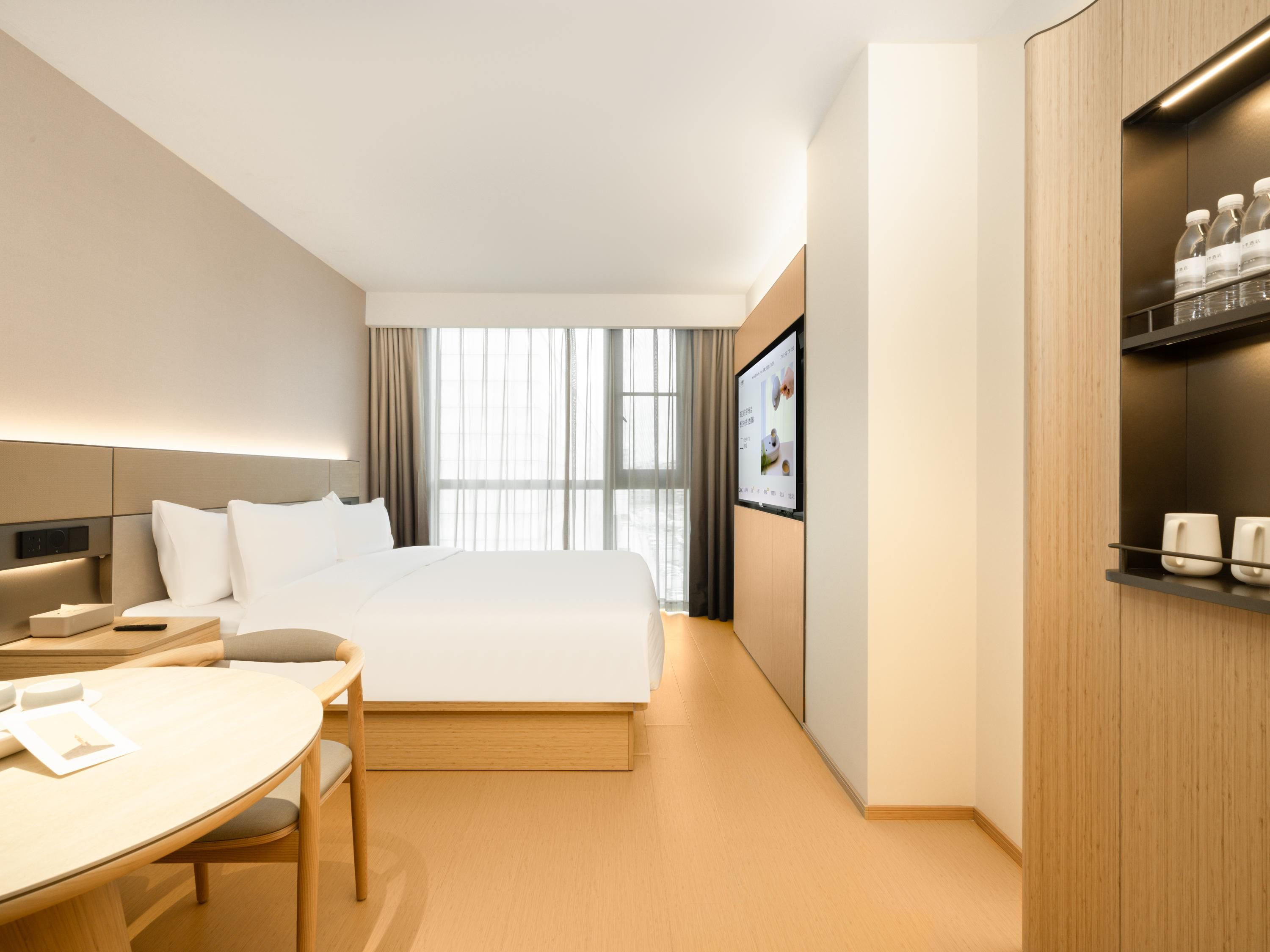 Quarto de hotel moderno com uma cama grande, uma escrivaninha e uma televisão.