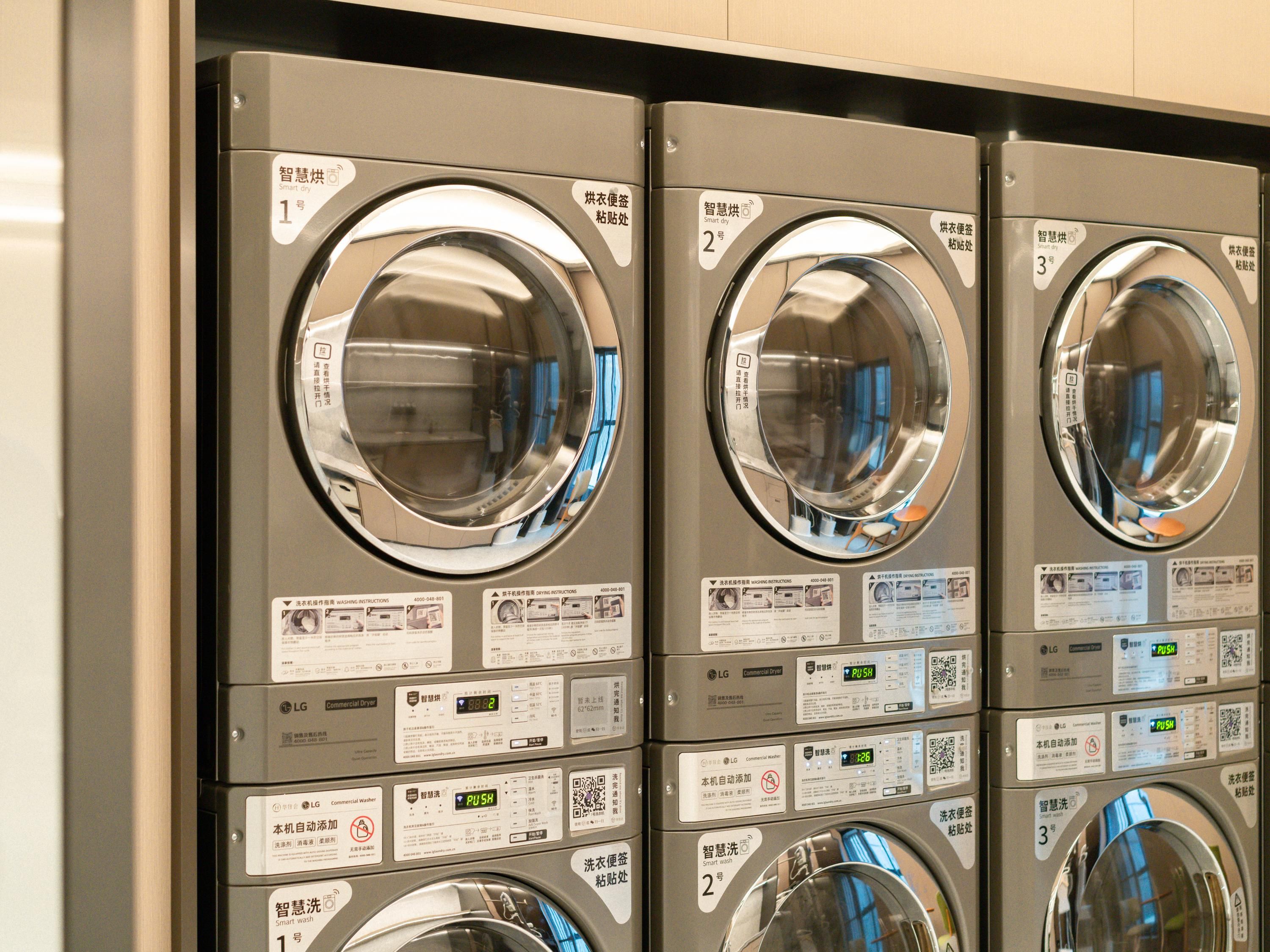 A row of commercial laundry machines with digital displays and control panels.