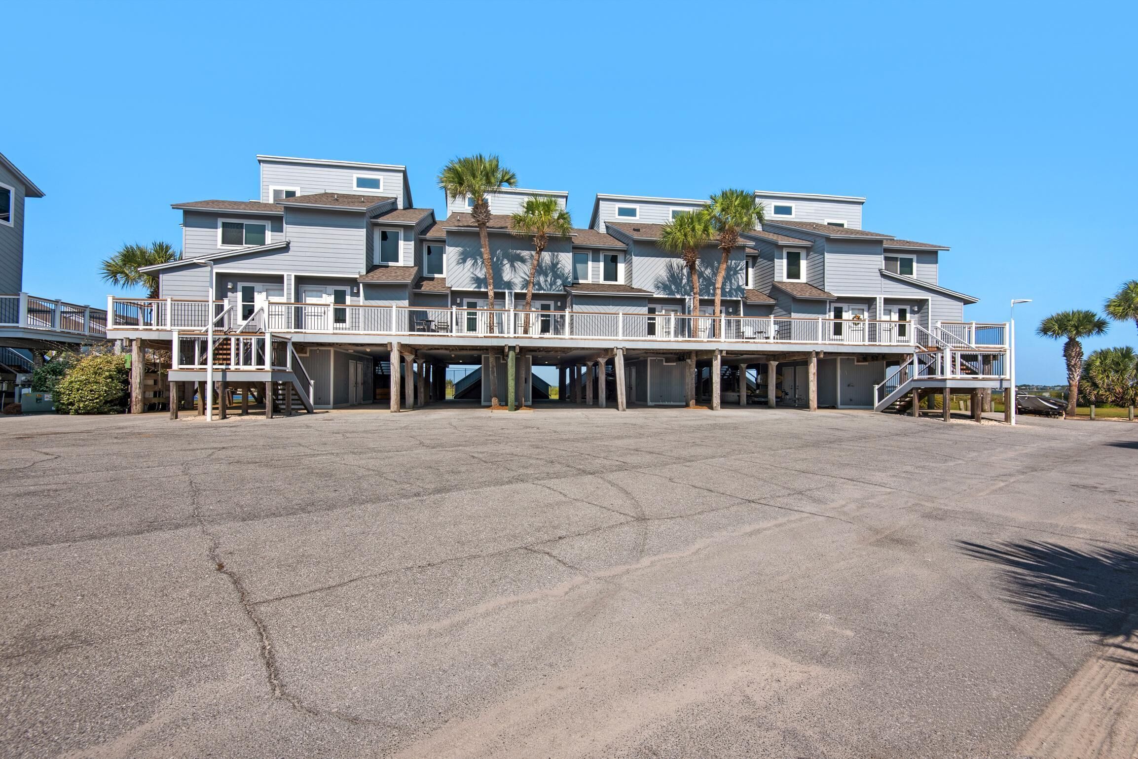 Et strandhotel med flere etager, udendørs altaner og palmer.