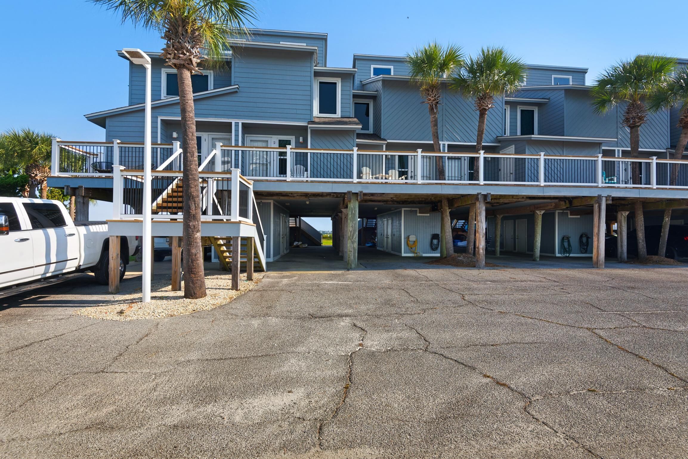 A multi-story beachfront property with a covered deck and a parking area.