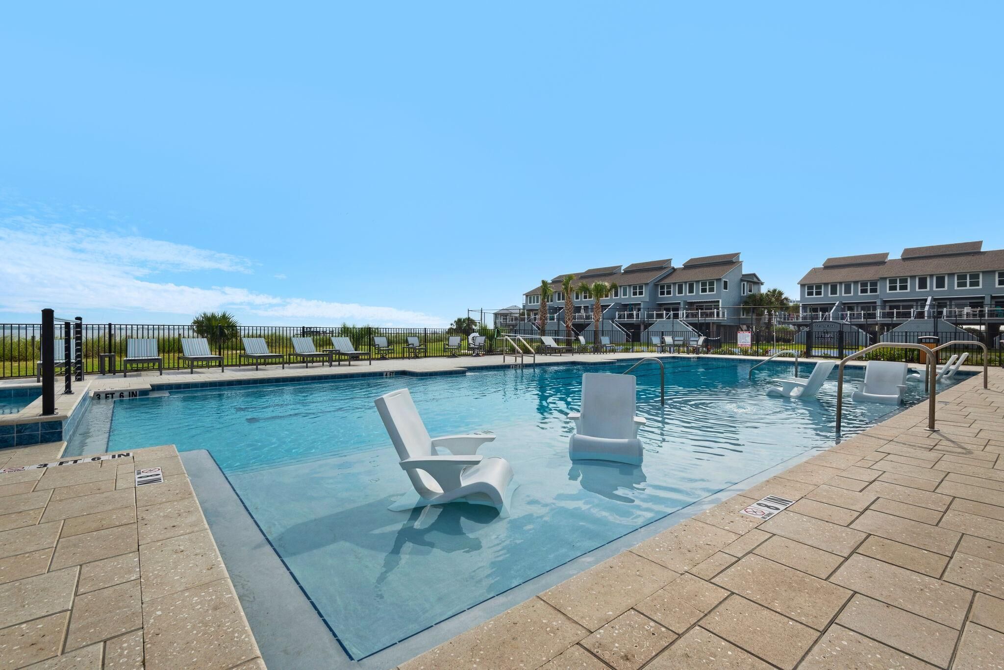 A swimming pool with lounge chairs and a clear view of a residential building in the background.