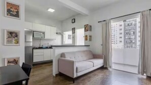 A modern apartment with a kitchenette, a dining area, and a living space with a sofa. - Cozy apartment in the best location in Itaim Bibi. (São Paulo)