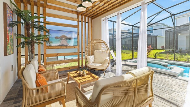 A sunlit room with wicker furniture, a hanging chair, and a view of a pool and ocean through large windows. - 2-Story Slide! Mickey & Minnie Clubhouse! MARIO Galaxy! Minion Room! (Clermont)