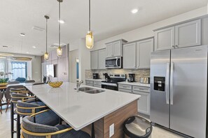 A modern kitchen with a central island, stainless steel appliances, and pendant lighting.