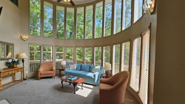 A spacious living room with a large windowed wall, a ceiling fan, and a blue sofa. - 21A Edelweiss w/ Hot Tub (Gatlinburg)