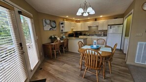 A compact kitchen with wooden cabinets, a dining table with chairs, and a chandelier. - 21A Edelweiss w/ Hot Tub (Gatlinburg)