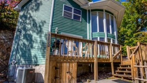 A two-story house with a wooden deck and a covered porch. - 21A Edelweiss w/ Hot Tub (Gatlinburg)