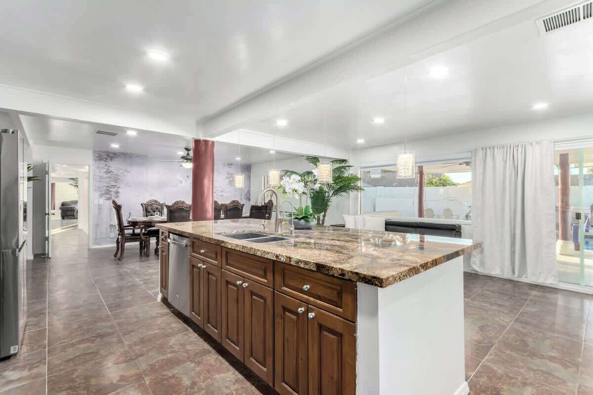 A modern kitchen with a granite countertop, wooden cabinets, and a central island.