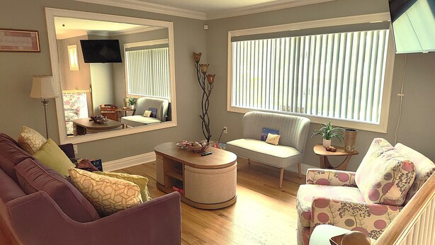 A living room with a sofa, armchair, ottoman, and a television.