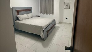 Un dormitorio con cama, luz de techo, ventana con cortinas y aire acondicionado instalado en la pared.