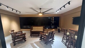 Una habitación amplia con ventilador de techo, un ventanal grande y una televisión de pantalla plana.