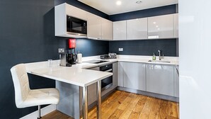 A modern kitchen with white cabinets, a built-in microwave, and a coffee machine.