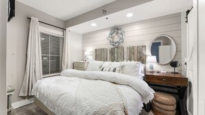 Een slaapkamer met een bed, nachtkastjes, een kaptafel, een spiegel en een aan de muur bevestigde krans.