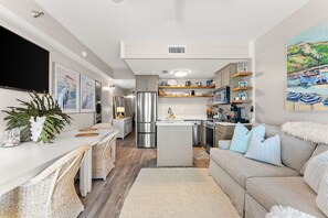 A modern kitchen with a central island, built-in appliances, and a dining area with wicker chairs.