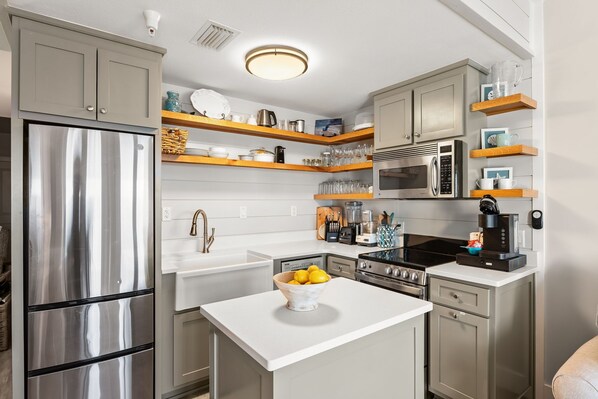 A modern kitchen with stainless steel appliances, wooden shelves, and a central island.
