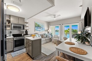 A modern kitchen with a microwave, stove, and cabinets. There is a dining area with a table and chairs, and a large window with a view of the outdoors.