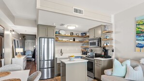 Een kleine keuken met een centraal eiland, inbouwapparatuur en open kasten.