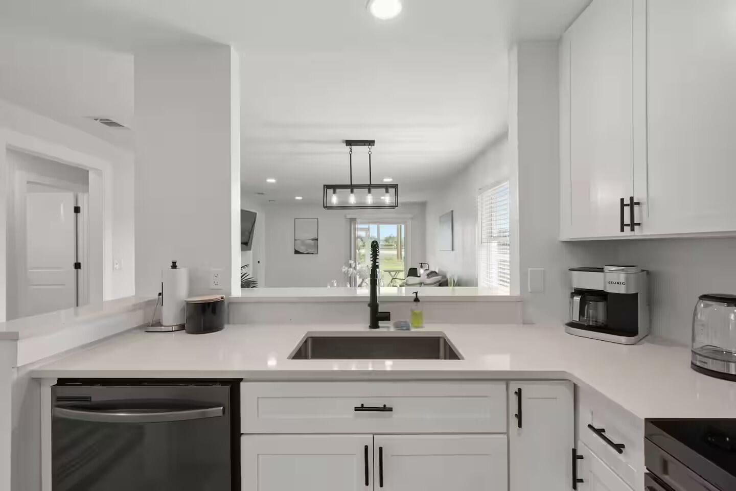 A modern kitchen with white cabinetry, a stainless steel sink, a coffee maker, and a dishwasher.