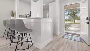 Una cocina moderna con una isla central, taburetes de bar y un reloj en la pared.