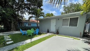 A residential property with a paved driveway, a lawn, and a blue chair. - Stylish 2BR Retreat in Miami's Design District! (Miami)