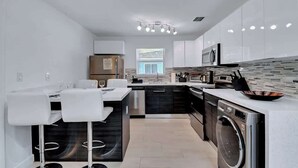A modern kitchen with a central island, built-in appliances, and a large window. - Stylish 2BR Retreat in Miami's Design District! (Miami)