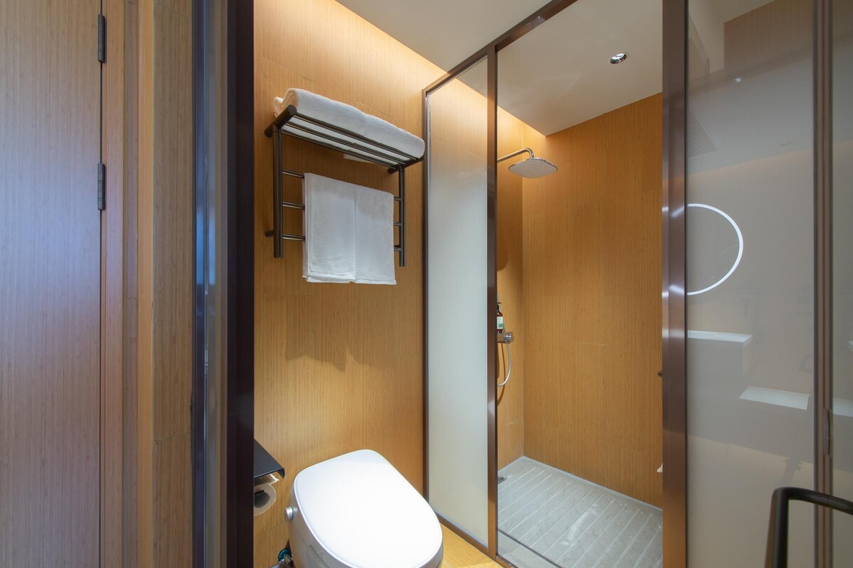 A modern bathroom with a toilet, a glass shower enclosure, and a towel rack.