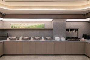 Une cuisine moderne équipée d’une cuisinière intégrée, d’un four à micro-ondes et d’une machine à café. On y trouve également plusieurs bocaux et récipients sur le plan de travail.