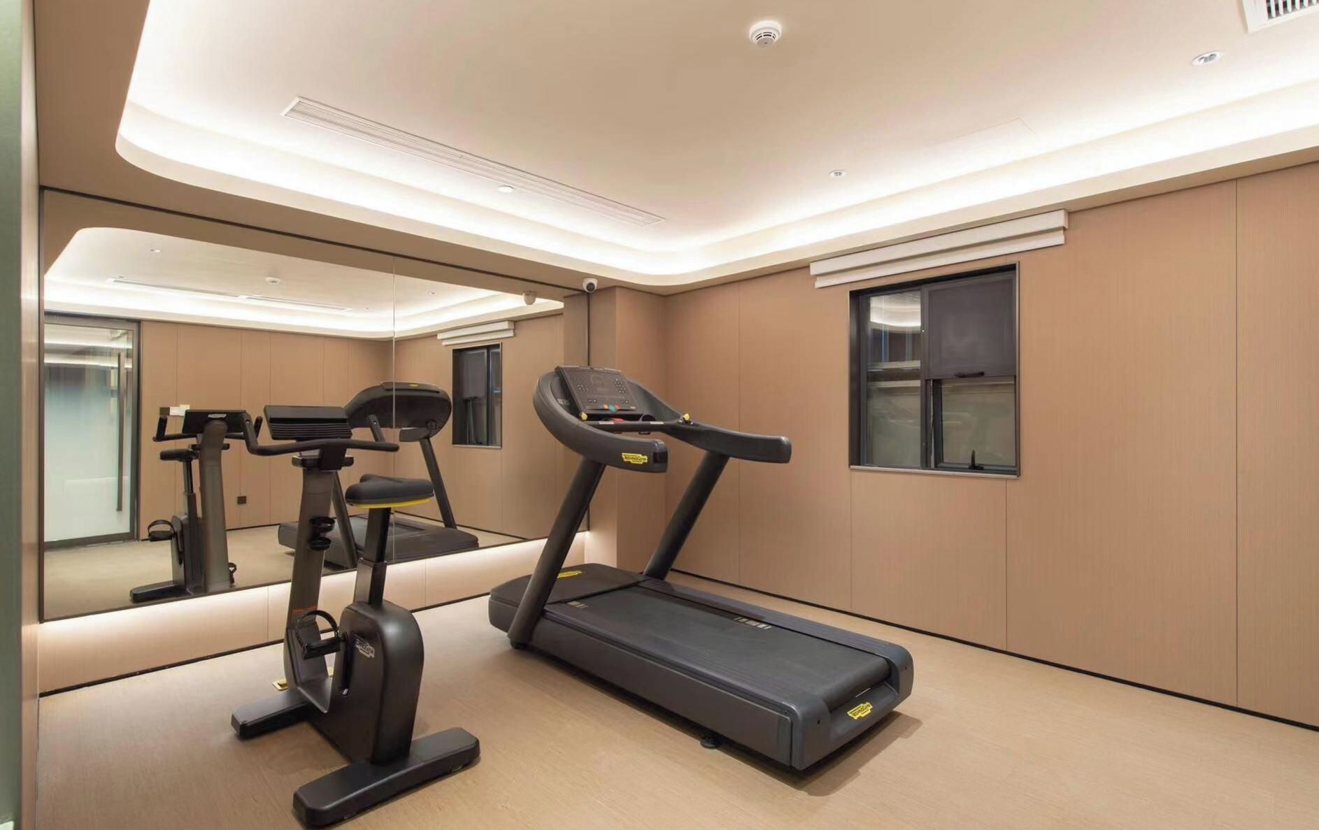 A modern gym with exercise equipment, a large mirror, and a window.