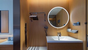 A modern bathroom with a wooden vanity, a round mirror with a light, a towel rack, and a shower area. - Ji Guangzhou Beijing Road Pedestrian St Cangbian (Guangzhou)