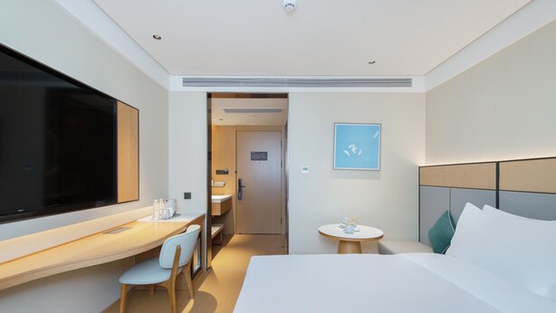 A modern hotel room with a large bed, a desk with a chair, a small round table, and a television. - Ji Guangzhou Beijing Road Pedestrian St Cangbian (Guangzhou)