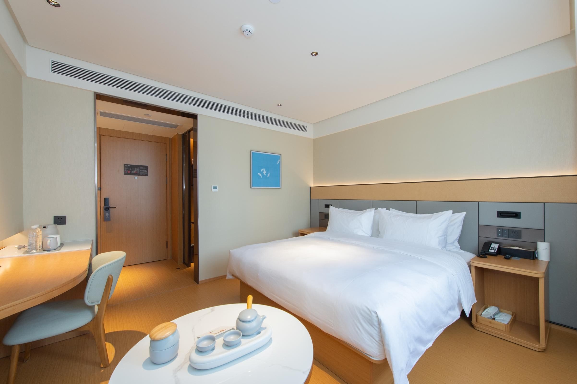 Une chambre d’hôtel comprenant un lit, un bureau, une chaise et une petite table avec un service à thé.