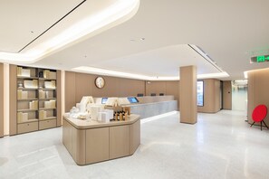 A modern reception area with a curved desk, a digital kiosk, and a bookshelf. - Ji Guangzhou Beijing Road Pedestrian St Cangbian (Guangzhou)