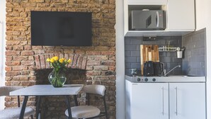 A kitchen with a brick wall, a flat-screen TV, a microwave, and a coffee maker. - Stylish & Petit Studio flat w/great tube connectio (Greater London)